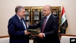 Iraqi President Barham Salih, right, instructs Prime Minister-designate Mohammed Allawi in Baghdad, Iraq, Feb. 1, 2020. Allawi was selected by rival Iraqi factions after weeks of political deadlock.