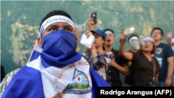 Manifestantes antigubernamentales entonan el himno nacional de Nicaragua el 25 de abril de 2018 frente a la sede de la policía nacional en Managua © AFP RODRIGO ARANGUA