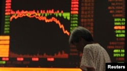An investor stands near an electronic board showing stock information in a brokerage house in Anhui, China July 27, 2015. China stocks plunged more than 8 percent, their biggest one-day drop in more than eight years. (REUTERS/Stringer)