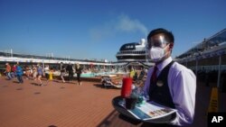 A waiter, wearing a mask for COVID-19 protection, holds a tray of drinks on the MSC Grandiosa cruise ship in Civitavecchia, near Rome, March 31, 2021.