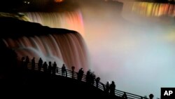 FILE - The American side of Niagara Falls and Horseshoe falls are lit up to celebrate the birth of the Duke and Duchess of Cambridge's son, George Alexander Louis. as people gather along the railing, July 23, 2013. 