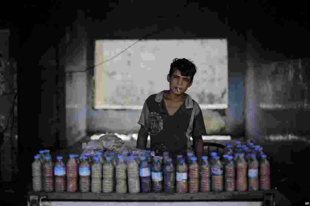 Abdul Aziz, 15, smokes a cigarette while waiting for customers to buy the mud from a sulphur well near the Hamam Alil spa south of Mosul, Iraq.