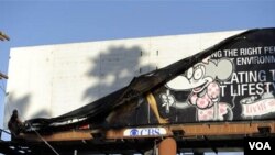 Un trabajador de la ciudad de LA removiendo una pancarta publicitaria que se alega fue alterada por el esténcil de Banksy.