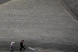 Workers clean steps near a recently erected office high-rise in Beijing, China, April 20, 2017.