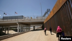 Un grupo de migrantes centroamericanos camina junto a la valla fronteriza de EE.UU. y México después de cruzar la frontera en El Paso, Texas, EE.UU.