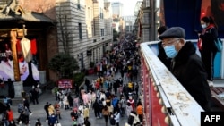 An elderly man looks on at people at a shopping centre in Wuhan, China’s central Hubei province on January 1, 2021. (Photo by NOEL CELIS / AFP)