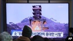 People watch a TV screen showing a file image of a ground test of North Korea's rocket engine during a news program at the Seoul Railway Station in Seoul, South Korea, Monday, Dec. 9, 2019.