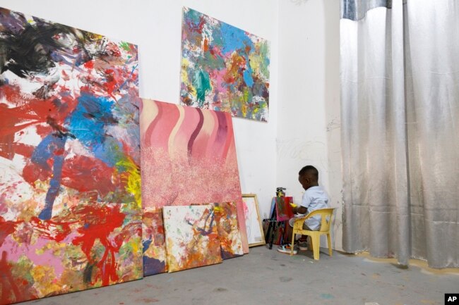 Ace-Liam Nana Sam Ankrah, who will turn two in July, paints amidst his own art work at his mother's art gallery in Accra, Ghana, Monday, May 27, 2024. (AP Photo/Misper Apawu)