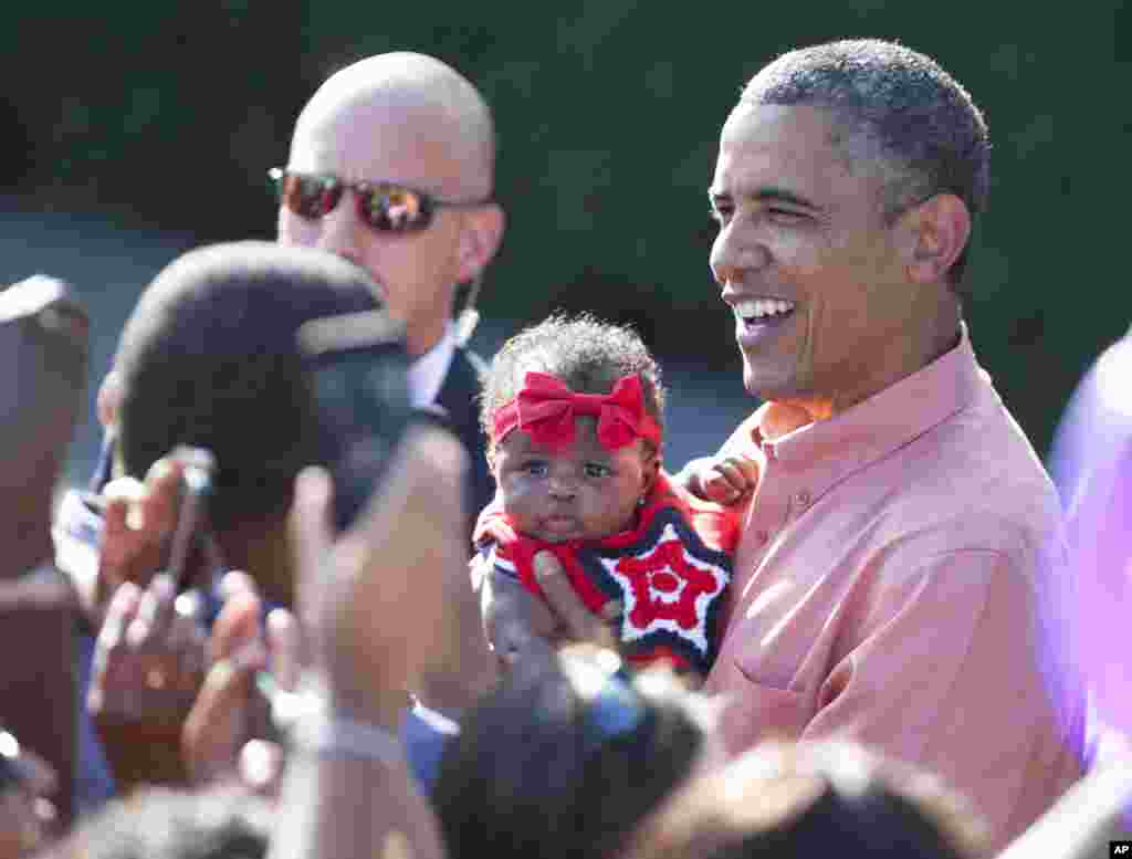 Presiden AS Barack Obama menggendong bayi saat menyapa para anggota militer dan keluarga mereka pada perayaan 4 Juli di halaman selatan Gedung Putih di Washington.