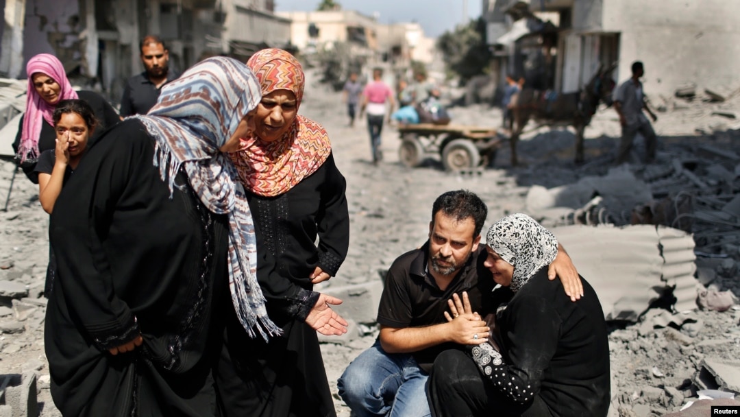 Một người đàn ông Palestine an ủi người thân cạnh ngôi nhà bị phá hủy của bà ở thị trấn Beit Hanoun, phía bắc Dải Gaza, 26/7/2014.