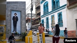 A man poses for a picture near a mural of Venezuelan Jose Gregorio Hernandez, known as the "Doctor of the Poor," after Pope Francis approved his canonization, making the doctor the nation's first saint, in Caracas, Venezuela, Feb. 25, 2025.