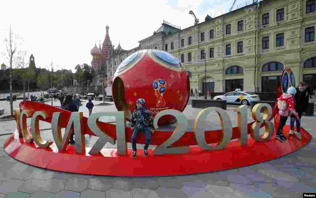 Para pengunjung berkumpul dekat dekorasi Piala Dunia FIFA 2018 dengan latar pemandangan gereja Katedral St. Basil, di pusat kota Moskow, Rusia, 7 Juni 2018. (Foto: Reuters)