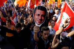 FILE - Supporters of Turkey's main pro-Kurdish Peoples' Democratic Party (HDP) hold masks of their jailed former leader Selahattin Demirtas during a rally in Ankara, Turkey, June 19, 2018.