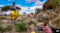 FILE - Joyce Ngui, left, fetches groundwater in Athi River, Machakos county, Kenya, Oct. 17, 2023