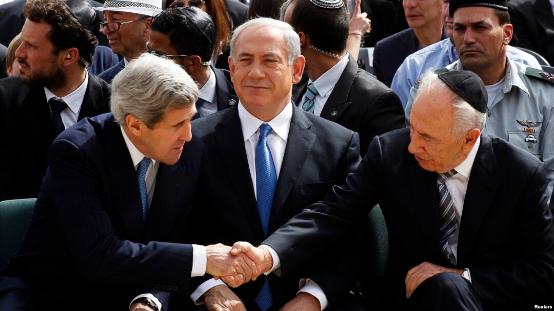 Presiden srael Shimon Peres berjabat tangan dengan Menlu AS John Kerry, sementara PM Netanyahu duduk diantara mereka saat upacara peringatan peristiwa Holocaust di Yad Vashem, Yerusalem (8/4).