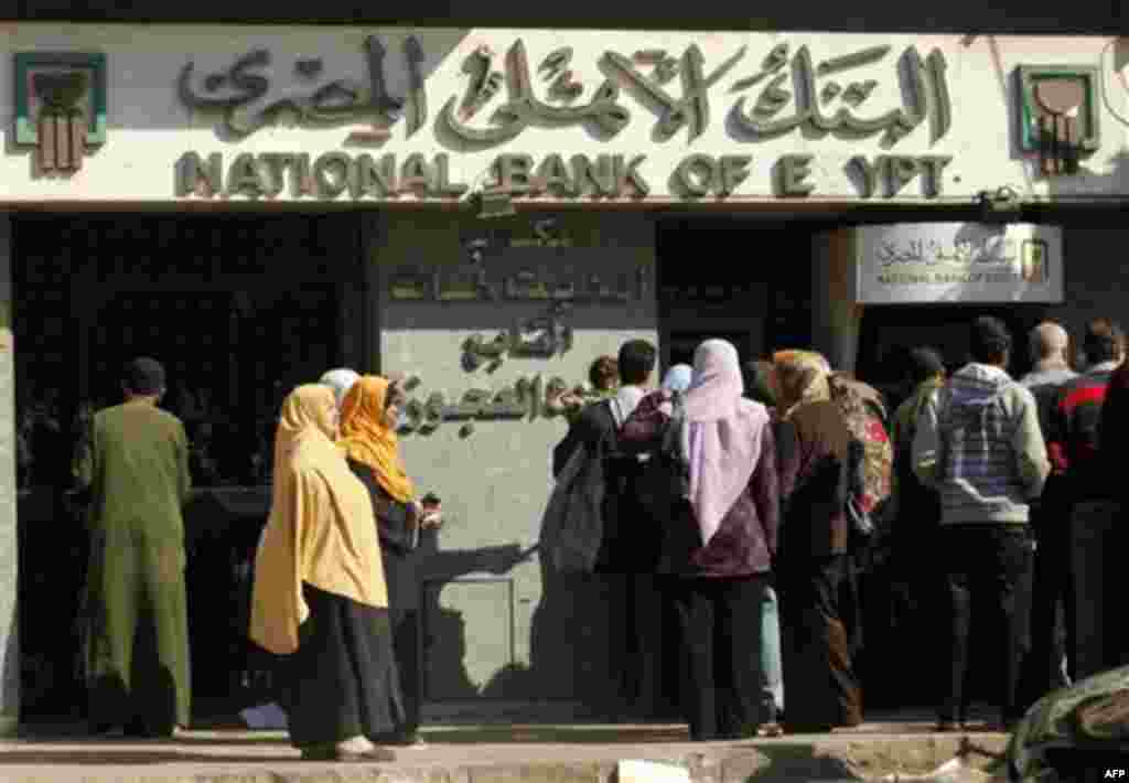 Egyptians wait at an automatic cash dispenser (ATM) in Cairo, Egypt, Feb 2, 2011