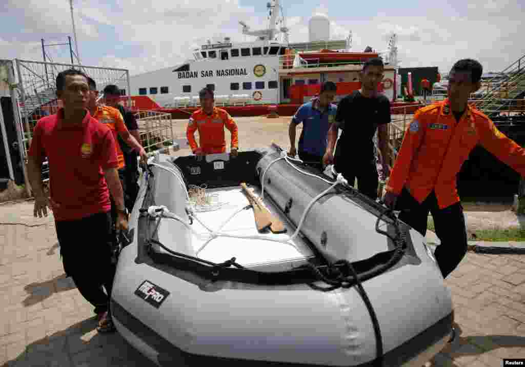 Rescue team members carry an inflatable boat in front of the SAR ship KN Purworejo during a search operation for passengers of AirAsia flight 8501 at Kumai port in Pangkalan Bun, Indonesia, Jan. 6, 2015.
