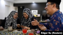 Tengku Shawal, a royal descendant, talks as his daughter Tengku Puteri (L) and his sister Tengku Intan (C) reminisce over old family photos at Intan's home in Singapore August 21, 2020. (REUTERS/Edgar Su)