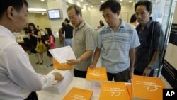 FILE - A staff distributes copies of the prospectus and brochures for the IPO of Alibaba, for the first day public offering at a local Hong Kong bank. 