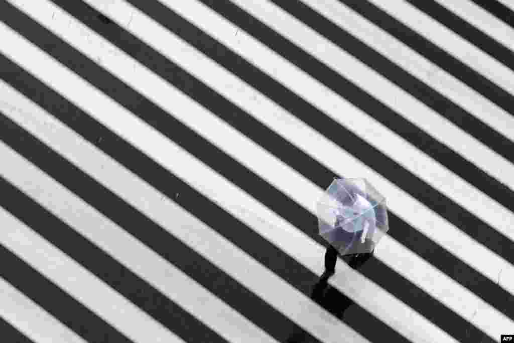 A pedestrian crosses a street on a rainy day in Tokyo.