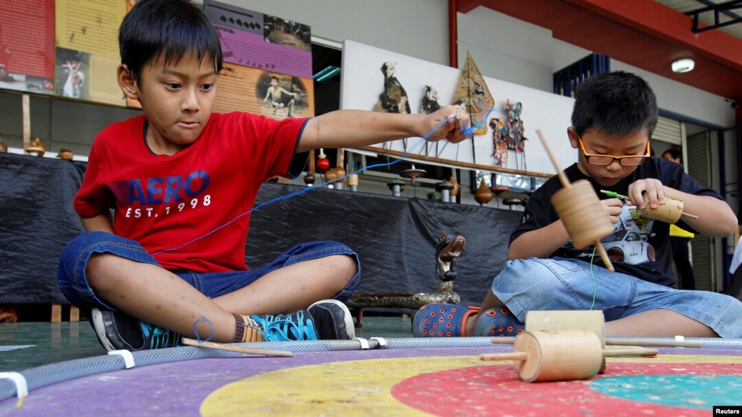 Dua orang anak laki-laki bermain gasing dalam acara permainan tradisional di sebuah sekolah di Jakarta (1/10). (Reuters/Iqro Rinaldi)