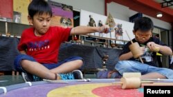 Dua orang anak laki-laki bermain gasing dalam acara permainan tradisional di sebuah sekolah di Jakarta (1/10). (Reuters/Iqro Rinaldi)