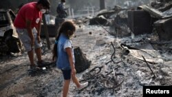 Ashley, tiga tahun, memandangi sepedanya yang terbakar setelah kebakaran hutan menghancurkan lingkungan di Bear Creek, Phoenix, Oregon, AS, 10 September 2020. (Foto: REUTERS/Carlos Barria)