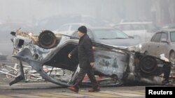 A man walks past a car that was burned during the protests triggered by fuel price increase in Almaty, Kazakhstan, Jan. 6, 2022. 