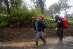 People walk around a road blocked by a landslide in San Cristobal Verapaz, Nov. 7, 2020, in the aftermath of Hurricane Eta. Searchers in Guatemala were digging through mud and debris looking for an estimated 100 people believed buried by a landslide.