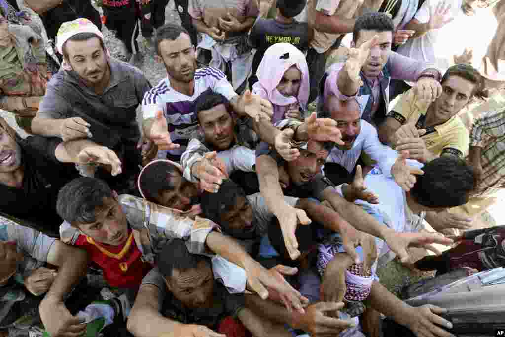 Displaced Iraqis from the Yazidi community gather for humanitarian aid at the Syria-Iraq border at Feeshkhabour border point, northern Iraq, Aug. 10, 2014.