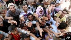 Displaced Iraqis from the Yazidi community gather for humanitarian aid at the Syria-Iraq border at Feeshkhabour border point, northern Iraq, Aug. 10, 2014.