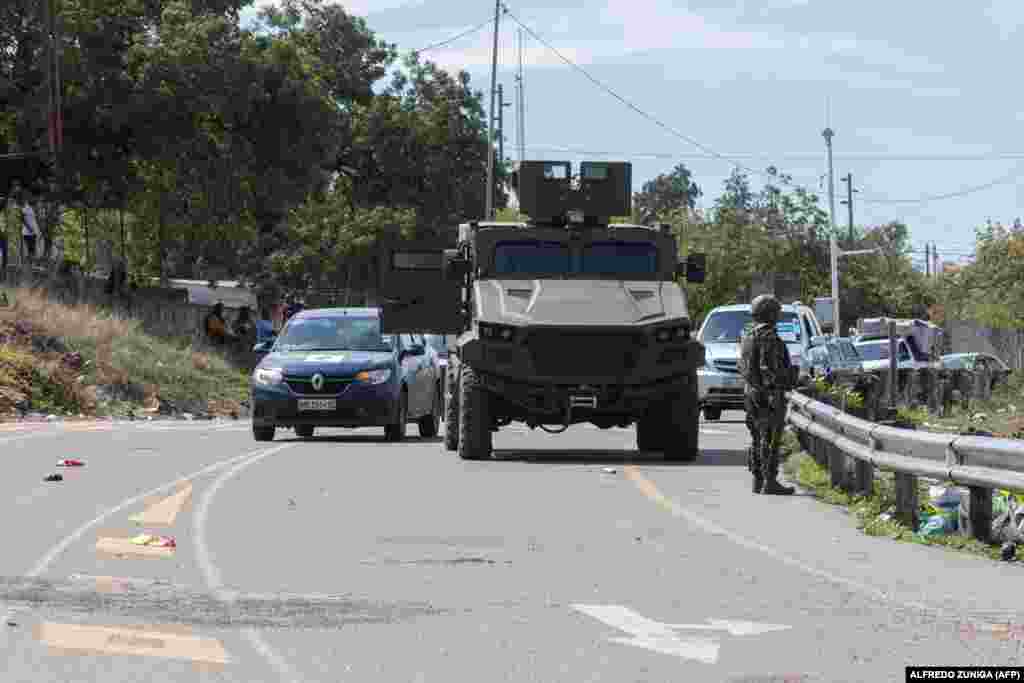 Um soldado moçambicano está ao lado de um veículo blindado enquanto escoltam veículos que tentam chegar ao posto fronteiriço de Ressano Garcia, entre Moçambique e a África do Sul.