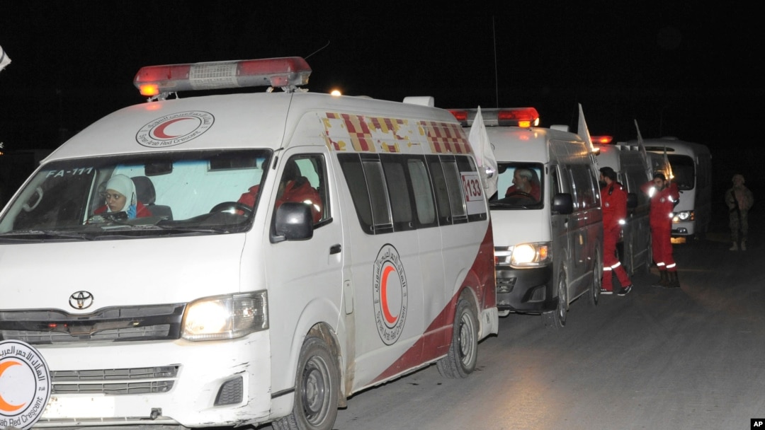 Photo released by the Syrian official news agency SANA, shows members of the Syrian Arab Red Crescent gathering near their ambulances during a human evacuation of sick and wounded people from the eastern Ghouta, near Damascus, Dec. 28, 2017. 