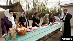 Pendeta Ortodoks Ukraina memercikkan air suci pada umat dan hidangan "paskha", sehari sebelum kebaktian Paskah di gereja Ortodoks di Luhansk, sebelah timur Ukraina (19/4). (Reuters/Vasily Fedosenko)