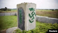 FILE - A monument with Nazi swastikas painted over it is seen in Jedwabne, Poland, Sept. 1, 2011. Polish prosecutors charged three men Tuesday for allegedly propagating Nazism after hidden camera footage of a group celebrating Adolf Hitler's birthday sparked uproar in the country.
