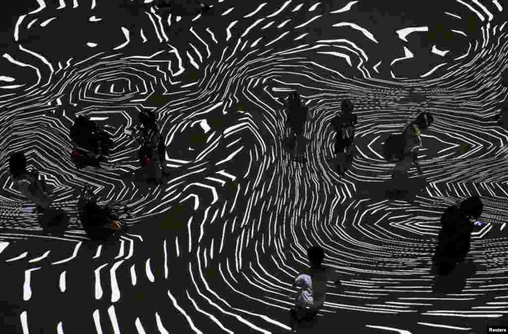 People interact with &quot;Pixel Wave 2015&quot; a projection art installation by France&#39;s Miguel Chevalier and local designers Carolyn Kan and Depression that features geometric patterns that react to movements and interactions of people, during the Singapore Night Festival at the Singapore Design Center.