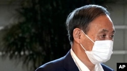 Japan's Chief Cabinet Secretary Yoshihide Suga wears a face mask as he walks to attend Prime Minister Shizo Abe's press conference at the prime minister's office in Tokyo on Aug. 28, 2020.