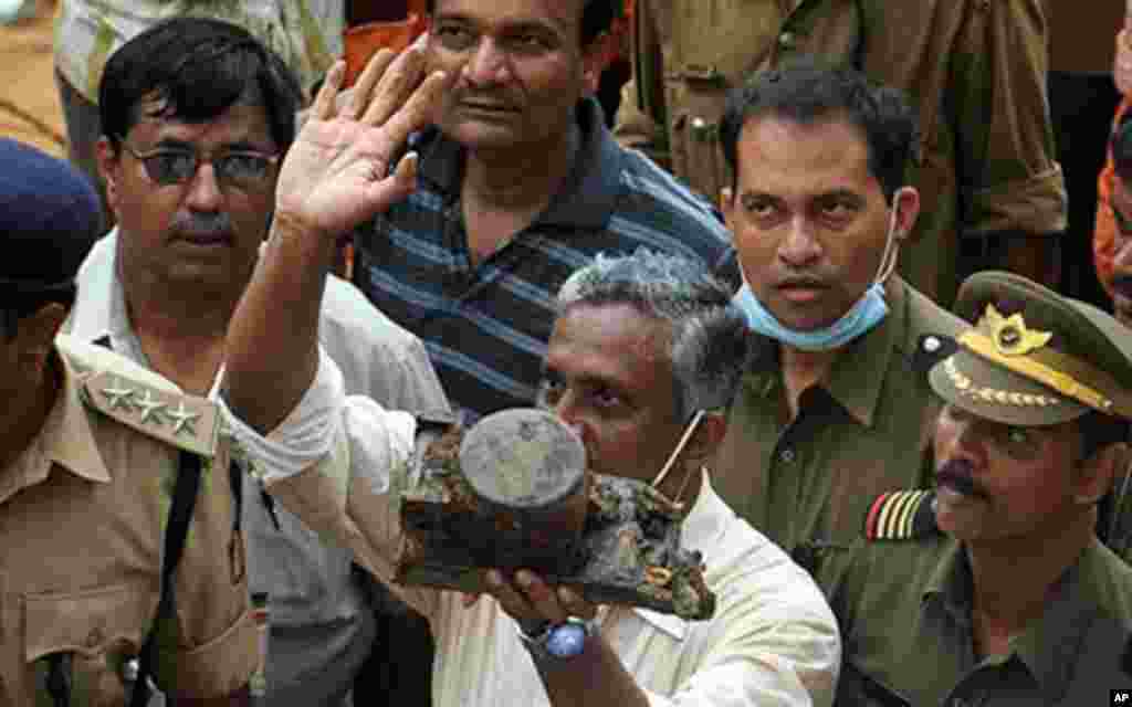 A Director General of Civil Aviation (DGCA) official (C) holds up an aircraft part which officials claim is the "black box" of the doomed Air India Express flight 812, discovered at the crash site in Mangalore on May 25, 2010. Investigators recovered May
