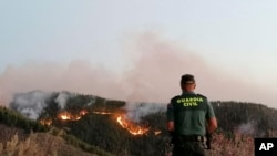  In this photo issued by the Guardia Civil, an officer looks at a forest fire in Gran Canaria, Spain, Aug. 11, 2019.