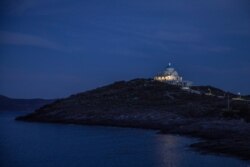 The church of Prophet Ilias is illuminated during the Good Friday procession of the Epitaphios, held without worshippers near the port town of Lavrio about 75 kilometers south of Athens on April 17, 2020.