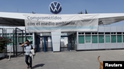 FILE - An employee leaves the Volkswagen plant as the company temporarily closes its factories in Mexico amid growing worries over the spread of the coronavirus disease, in Puebla, Mexico, March 29, 2020.