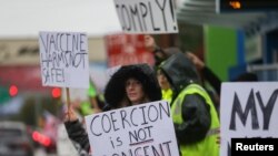 Seorang perempuan memegang poster yang berisi protes terhadap pemberlakuan mandat vaksin dalam aksi unjuk rasa di luar kantor perusahaan penerbangan Boeing di Everett, Washington, pada 15 Oktober 2021. (Foto: Reuters/Lindsey Wasson)