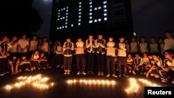 FILE - Students hold candles outside their dormitory during a ceremony to mark the anniversary of Japan's invasion of China in Zhuji, Zhejiang province, Sept. 17, 2013.