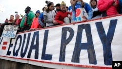 FILE - Fans stand behind a large sign for equal pay for the women's soccer team during a match between the United States and Colombia in East Hartford, Conn. The World Economic Forum's annual Global Gender Gap Report released on Oct. 25, 2016, found that the global gender pay gap will not be closed for another 170 years if current trends continue.