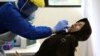 A woman reacts as she has her nasal swab sample collected by a health worker during a mass test for the new coronavirus in Jakarta, Indonesia, June 21, 2020. 