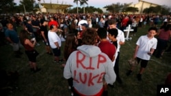 Zachary Haupert, 14, painted "RIP Luke," on his hoodie in honor of his friend Luke Hoyer, who was one of the victims of the shooting at Marjory Stoneman Douglas High School, as he attends a candlelight vigil, Feb. 15, 2018, in Parkland, Florida. 