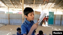 FILE PHOTO: A child reads a book in a makeshift school run by Rohingya teachers in Kutupalong refugee camp in Cox’s Bazar, Bangladesh, Feb. 7, 2019