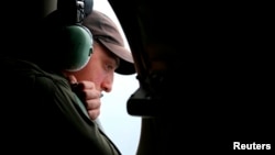 A crew member looks out an observation window from a Royal Australian Air Force (RAAF) AP-3C Orion aircraft while searching for the missing Malaysia Airlines Flight MH370 over the southern Indian Ocean, March 26, 2014.