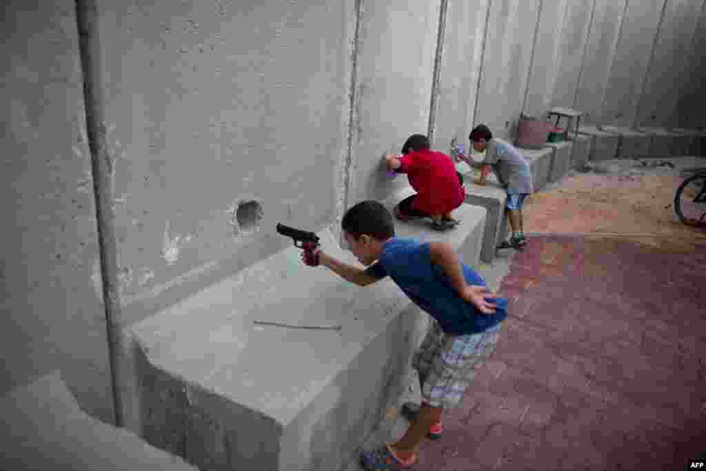 Israeli children play with toy guns next to cement walls built to protect a kindergarten in the center of Kibbutz Nahal Oz, near the border with Gaza Strip.
