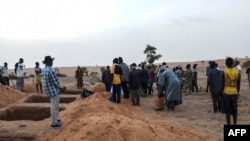 FILE - Officials and residents stand near freshly dug graves on June 11, 2019, in a Dogon village in Mali, after an attack on ethnic Dogon on June 9, 2019. 